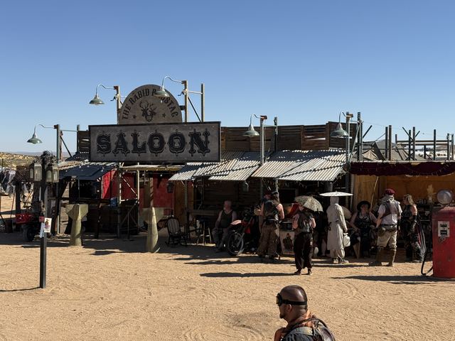 Wastelanders gathered outside a frontier-style saloon on a sunny afternoon.