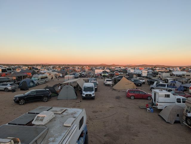 Wide view of the sprawling campground at dusk, tents and RVs to the horizon.