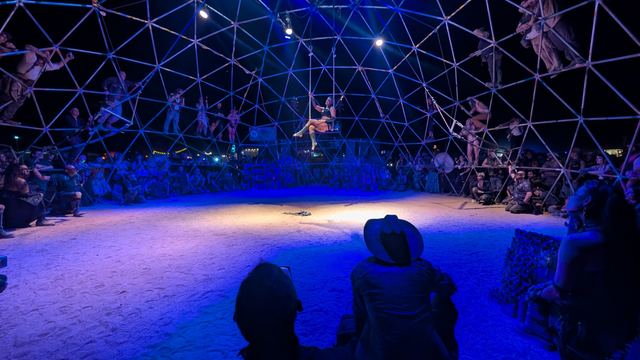 Wide shot of the Thunderdome floor under blue light, spectators ringing the dome.