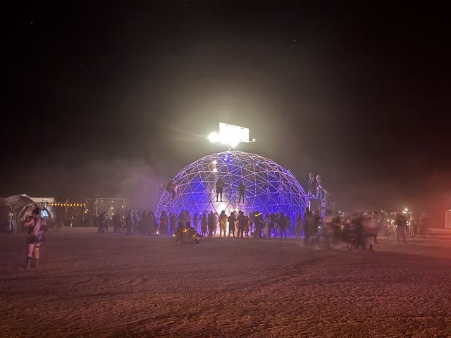 The Thunderdome glowing purple at night across the dark festival grounds.