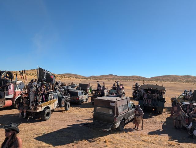 Pickups and war rigs flying black flags on the open desert.