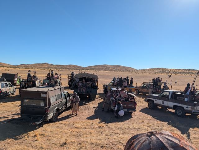 Armored pickups loaded with riders spread across the dry flats.