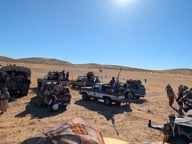 Convoy vehicles idling in a wide circle on the desert.