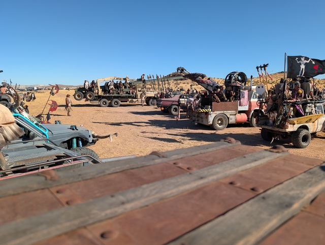 Riders perched on decorated pickups with axes, the convoy lined up behind.