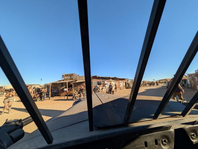 Another look through the barred windshield at shacks and walkers.