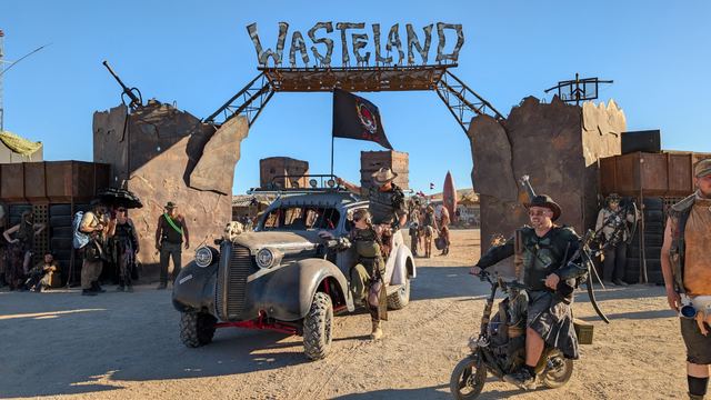 The war car under the gate with a motorcycle rider passing by.